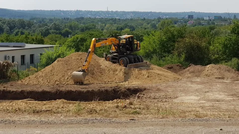 Kotrógép a kiásott alap és a földkupac mellett